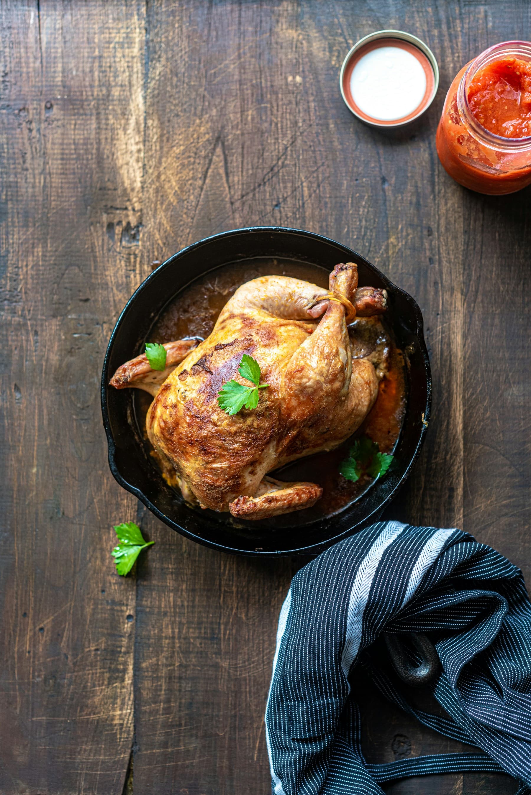 Golden whole roasted chicken served in a skillet with herbs